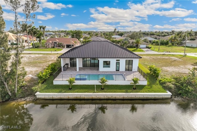 back of property featuring a patio area, a yard, and a water view