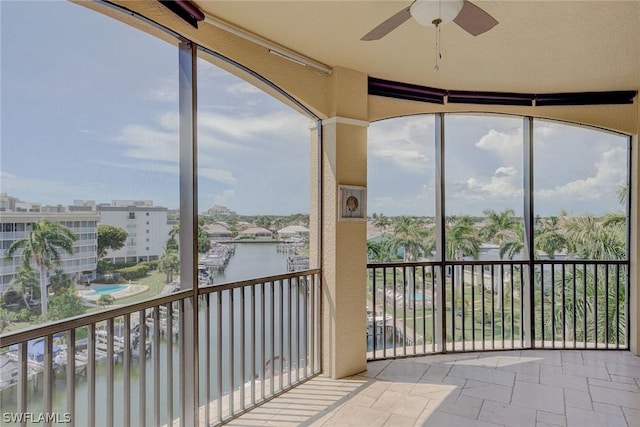 unfurnished sunroom with a water view, a wealth of natural light, and ceiling fan