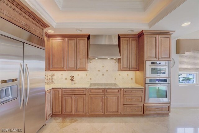 kitchen featuring appliances with stainless steel finishes, light tile patterned floors, decorative backsplash, light stone countertops, and wall chimney exhaust hood