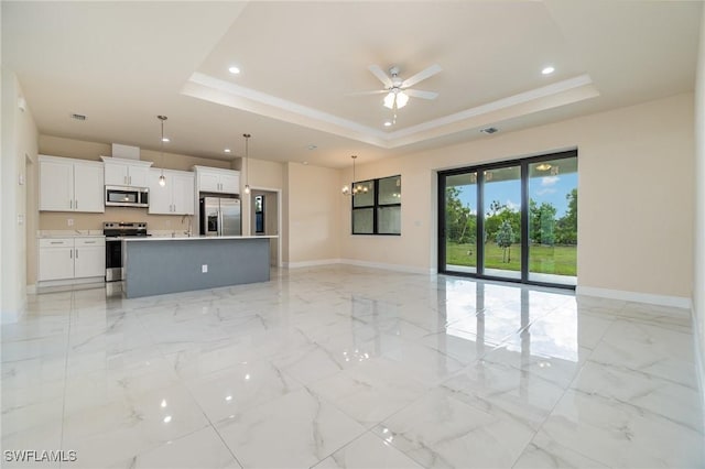 unfurnished living room featuring ceiling fan, ornamental molding, and a raised ceiling