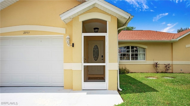 doorway to property with a garage and a lawn