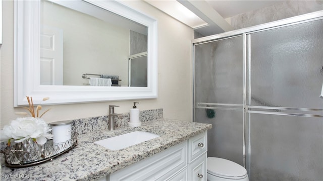 bathroom with vanity, toilet, and a shower with shower door