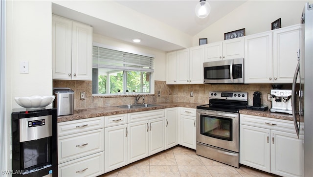 kitchen with tasteful backsplash, stainless steel appliances, sink, vaulted ceiling, and white cabinets