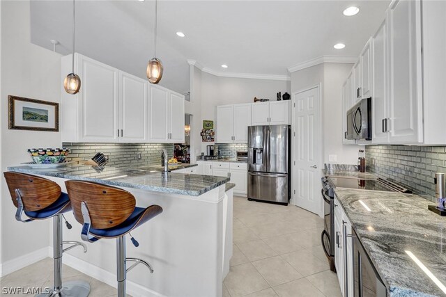 kitchen with white cabinets, a kitchen breakfast bar, decorative light fixtures, kitchen peninsula, and stainless steel appliances