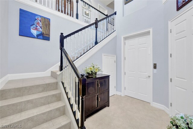 stairway with tile patterned floors and a high ceiling