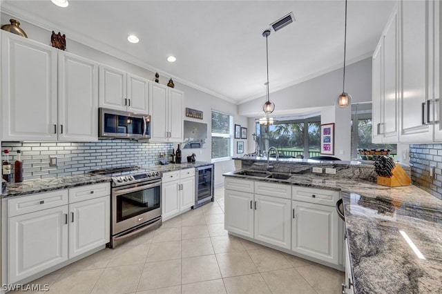 kitchen with appliances with stainless steel finishes, backsplash, sink, decorative light fixtures, and white cabinets