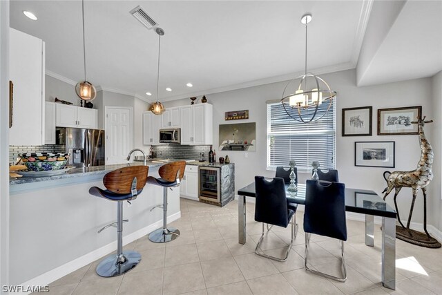 dining space featuring an inviting chandelier, beverage cooler, ornamental molding, and light tile patterned flooring