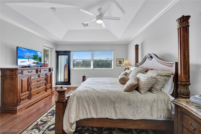 bedroom featuring a tray ceiling, ceiling fan, wood-type flooring, and ornamental molding