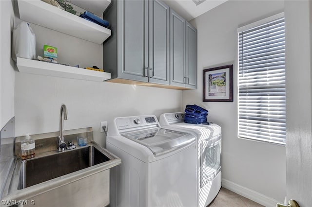 clothes washing area featuring cabinets, light tile patterned floors, washing machine and dryer, and sink