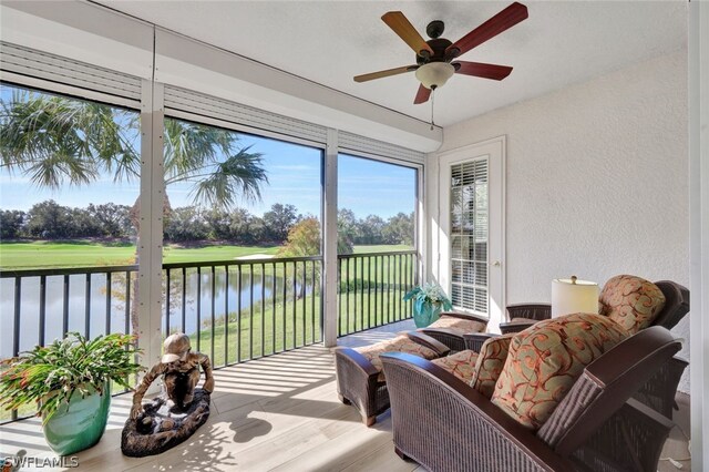 sunroom featuring a water view and ceiling fan