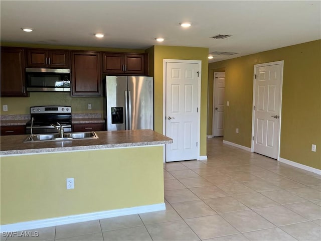 kitchen featuring light tile patterned flooring, sink, dark brown cabinetry, and stainless steel appliances