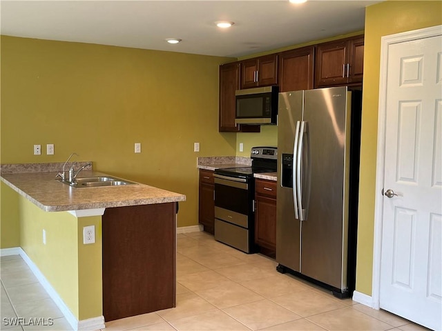 kitchen featuring sink, dark brown cabinetry, light tile patterned flooring, kitchen peninsula, and stainless steel appliances