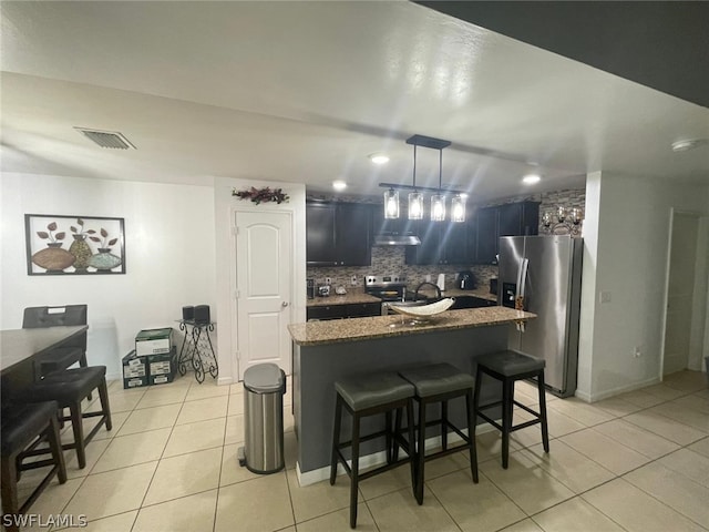 kitchen featuring a kitchen bar, appliances with stainless steel finishes, tasteful backsplash, pendant lighting, and light tile patterned floors