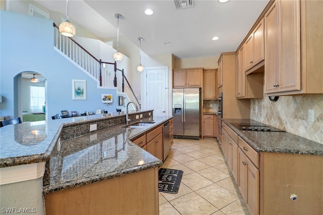 kitchen with ceiling fan, dark stone countertops, sink, hanging light fixtures, and appliances with stainless steel finishes