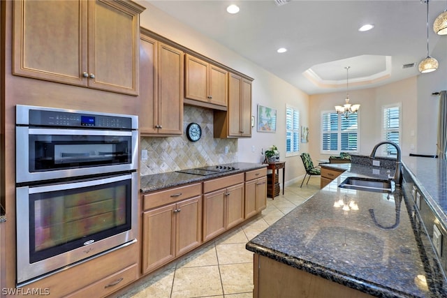 kitchen with a notable chandelier, a raised ceiling, sink, hanging light fixtures, and double oven