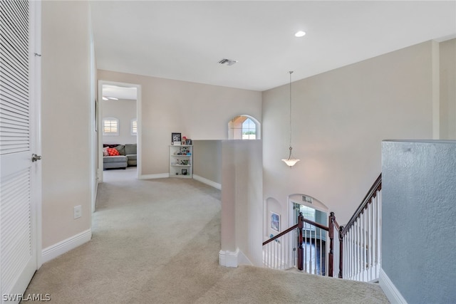 corridor featuring light colored carpet and a wealth of natural light