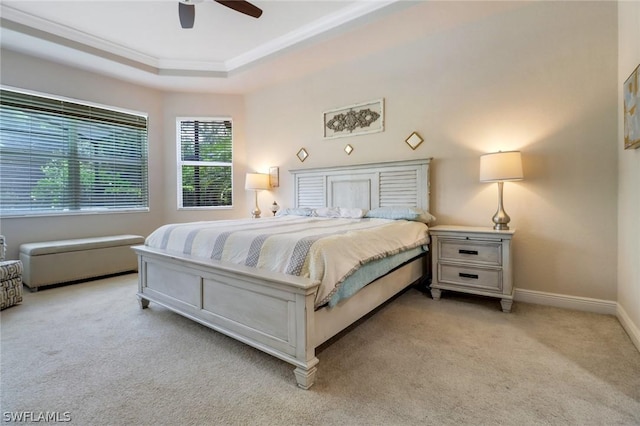 carpeted bedroom featuring ceiling fan and a raised ceiling