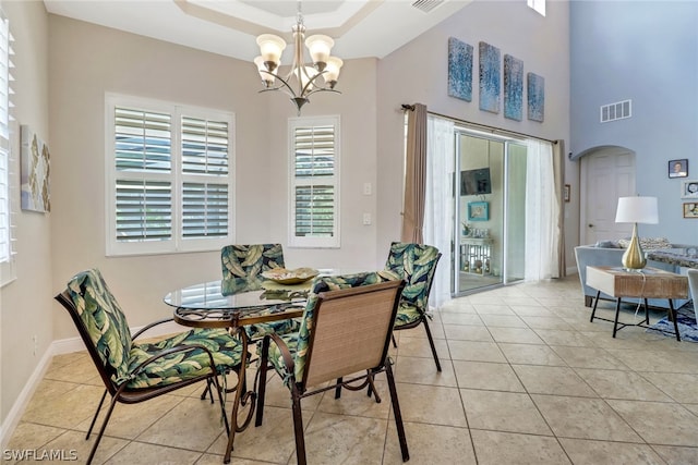 dining area featuring a tray ceiling, light tile patterned floors, and a notable chandelier