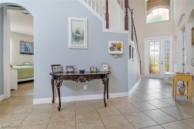 foyer entrance featuring french doors, light tile patterned floors, and a towering ceiling