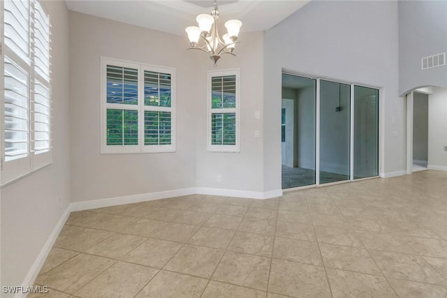 7787 Martino Cir, Naples, FL 34112 - empty room with a chandelier, arched walkways, a high ceiling, and light tile patterned floors