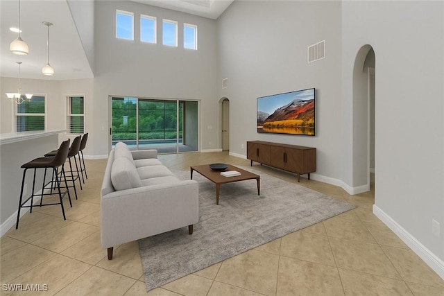 7787 Martino Cir, Naples, FL 34112 - living room featuring arched walkways, light tile patterned flooring, a chandelier, and a high ceiling