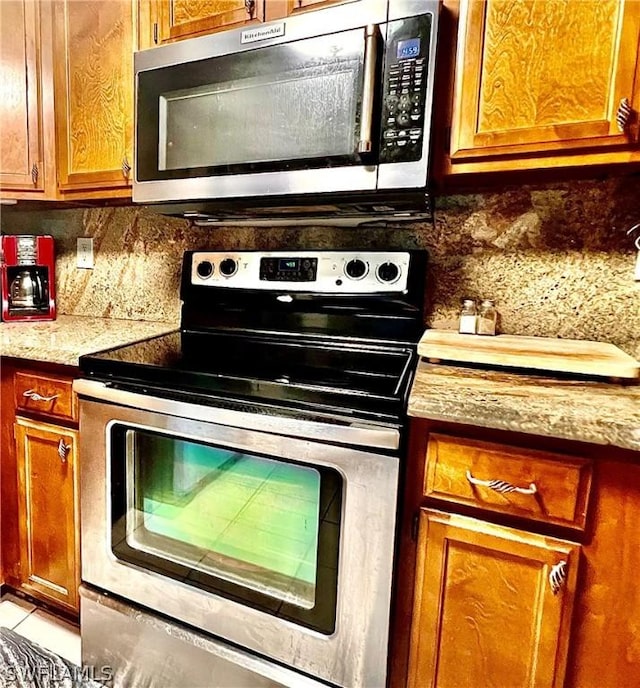 kitchen featuring appliances with stainless steel finishes, tasteful backsplash, light countertops, and brown cabinetry