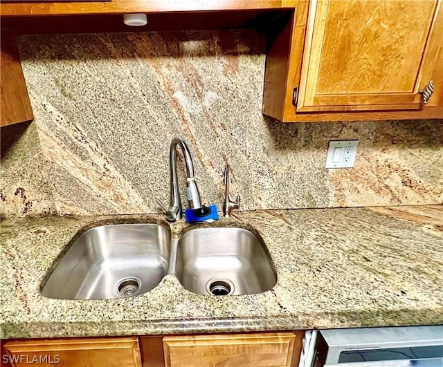 kitchen view of a sink, backsplash, light countertops, and brown cabinets