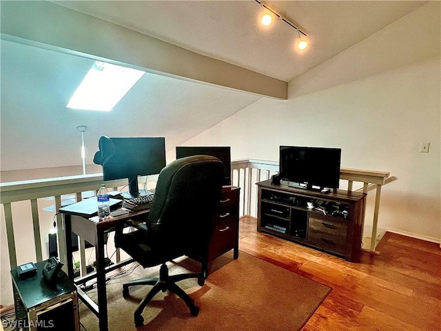 office featuring lofted ceiling, rail lighting, wood finished floors, and baseboards