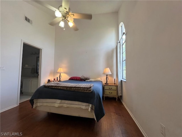 bedroom featuring baseboards, wood finished floors, ensuite bath, and a ceiling fan