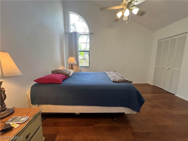 bedroom with dark wood finished floors, a ceiling fan, a closet, lofted ceiling, and baseboards