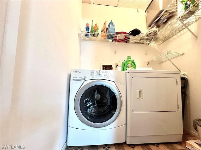 washroom with washing machine and dryer and wood finished floors