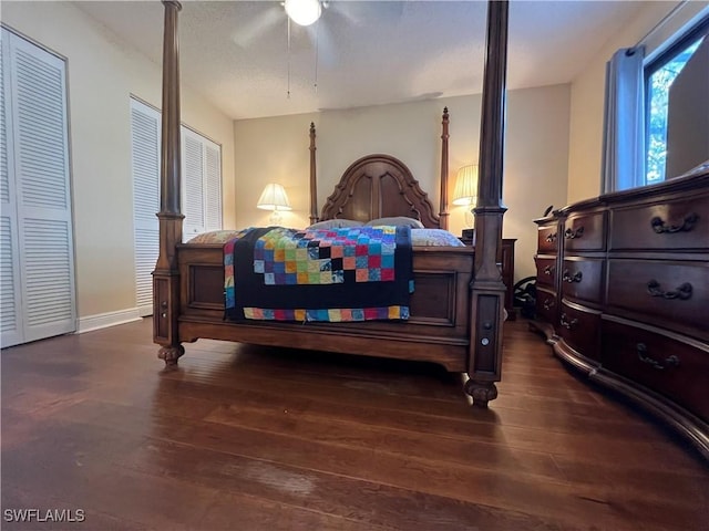 bedroom with wood-type flooring, ceiling fan, baseboards, and two closets
