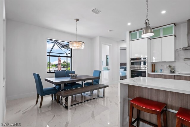 kitchen featuring backsplash, white cabinets, stainless steel double oven, and decorative light fixtures