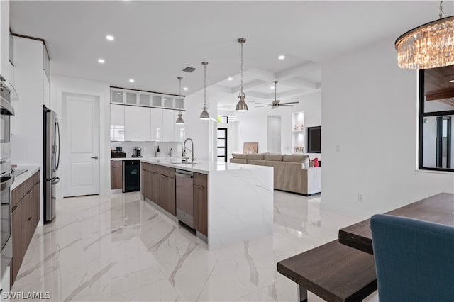 kitchen featuring pendant lighting, a large island with sink, white cabinets, sink, and appliances with stainless steel finishes