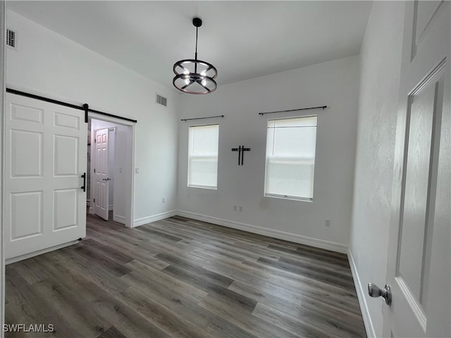 unfurnished dining area with an inviting chandelier, a barn door, and hardwood / wood-style flooring