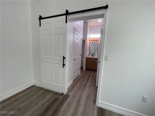 corridor featuring a barn door and wood-type flooring