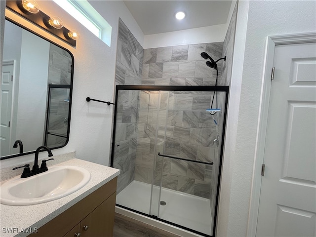 bathroom featuring walk in shower, vanity, and hardwood / wood-style flooring