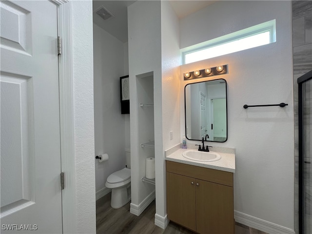 bathroom with a shower with shower door, hardwood / wood-style flooring, vanity, and toilet