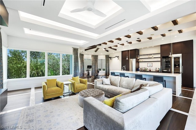 living room with wood-type flooring, ceiling fan, and a tray ceiling