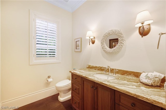 bathroom featuring hardwood / wood-style flooring, ornamental molding, toilet, and vanity