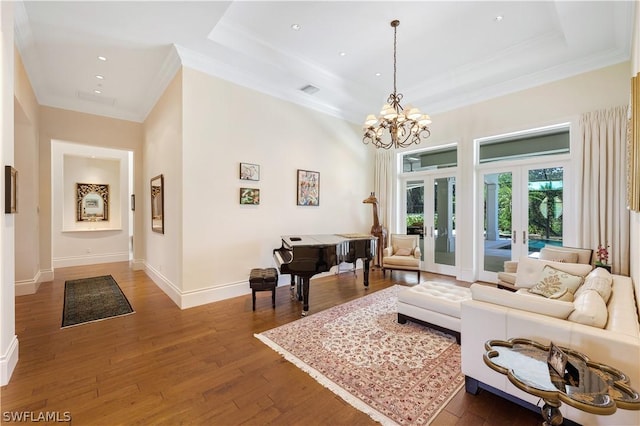 living room with french doors, a tray ceiling, dark wood-type flooring, and a notable chandelier