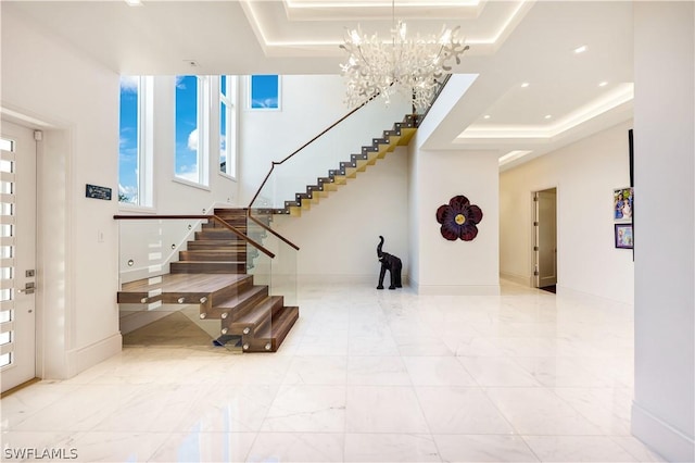 foyer with a raised ceiling and a notable chandelier