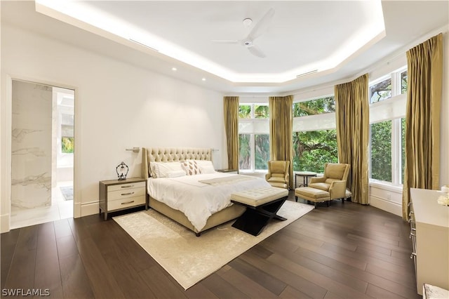 bedroom featuring dark hardwood / wood-style floors, ceiling fan, and a tray ceiling