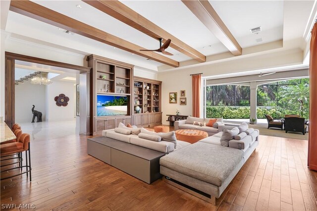 living room featuring hardwood / wood-style flooring, ceiling fan with notable chandelier, and beamed ceiling