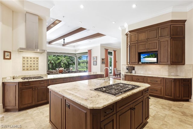 kitchen with stainless steel gas stovetop, extractor fan, and a kitchen island with sink