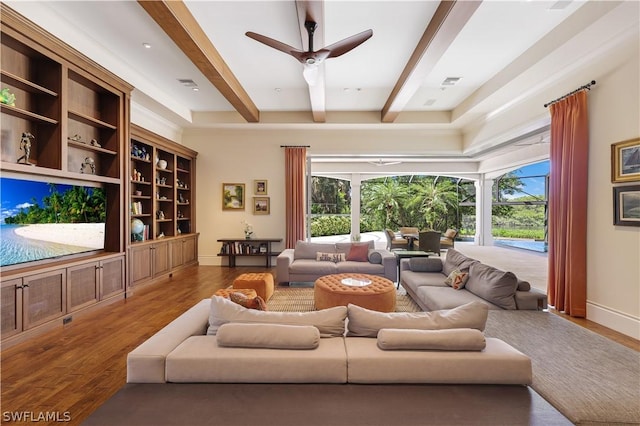 living room featuring ceiling fan, hardwood / wood-style flooring, a wealth of natural light, and beamed ceiling