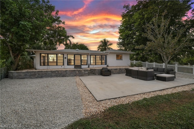 back house at dusk featuring an outdoor living space and a patio area