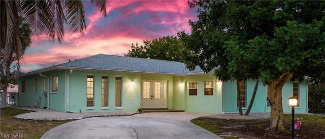 single story home featuring a shingled roof, concrete driveway, and stucco siding