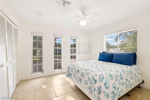 bedroom with ceiling fan, visible vents, a closet, and light tile patterned flooring