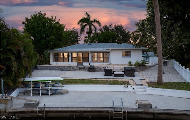 back of property at dusk with a patio area, fence, and an outdoor living space